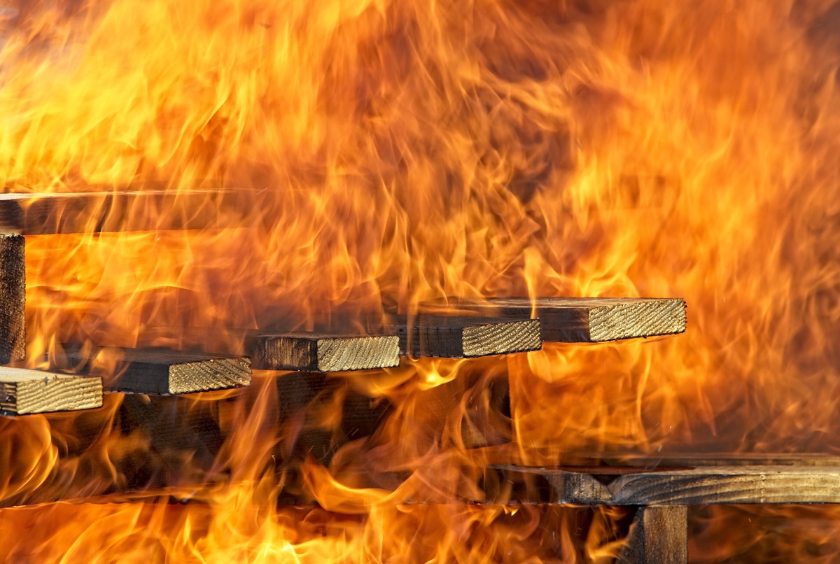 Close-up of several timber planks being engulfed in bright orange flames during a fire test. Demonstrates how timber density is tested for BAL compliance.